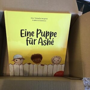 Das Buch "Eine Puppe für Ashé" in einem Karton